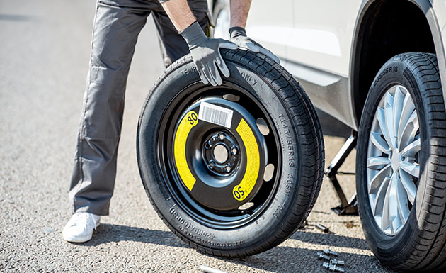 Worker changing car wheel on the road